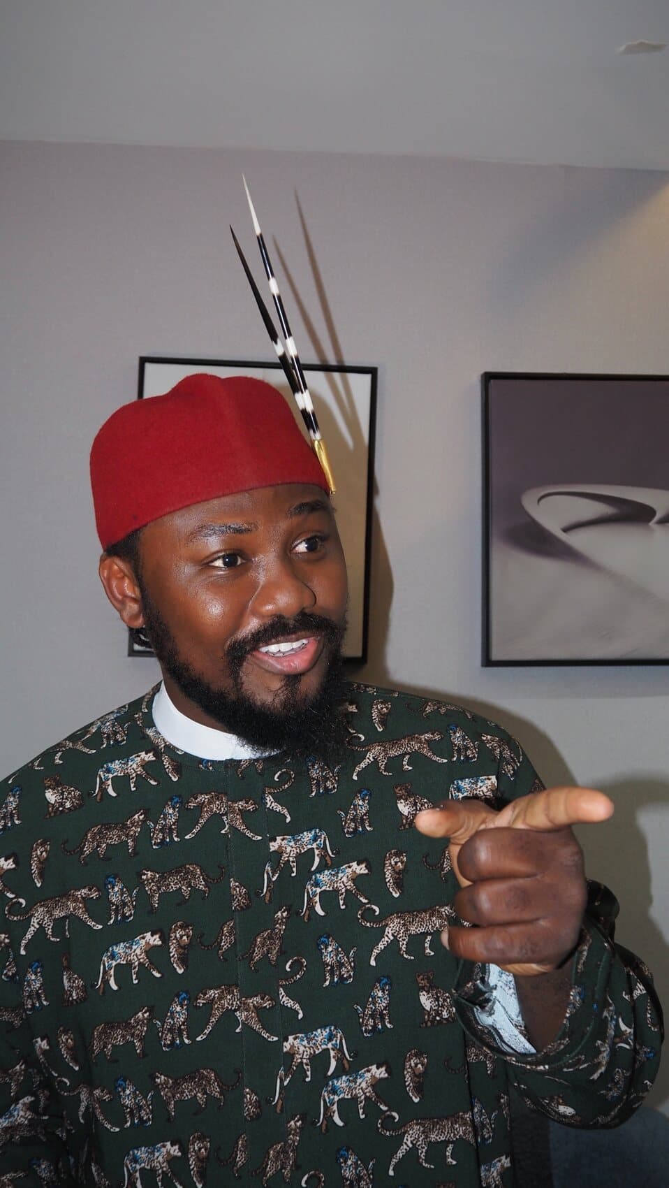 ABJKOREA wearing a red Igbo chieftaincy cap with porcupine quill and a green leopard-print agbada.