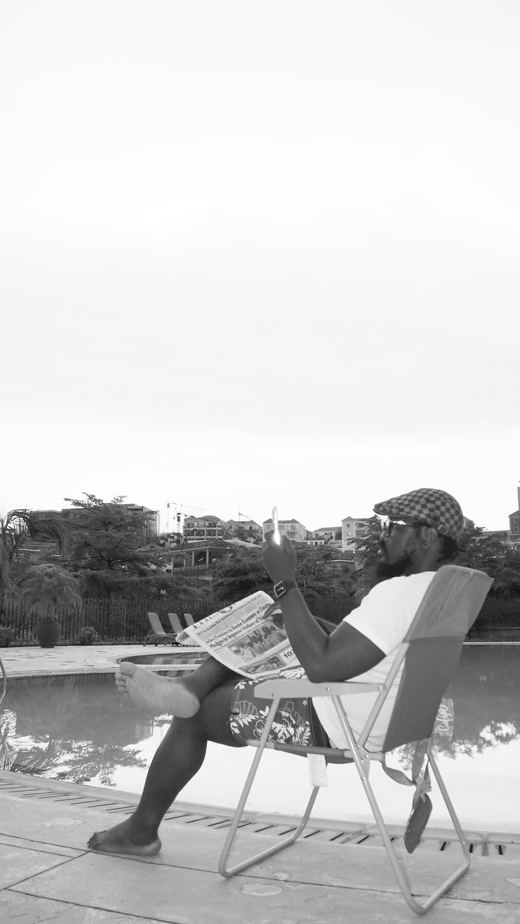 ABJKOREA reading the morning newspaper poolside in black and white — a daily discipline of staying informed.